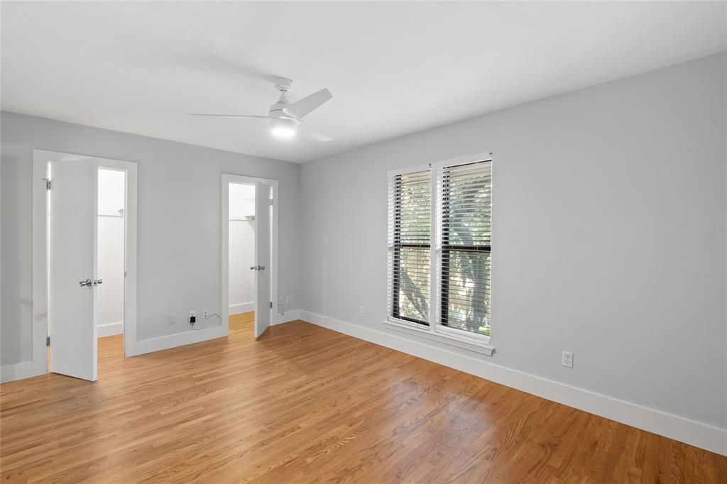 Unfurnished bedroom with a walk in closet, light wood-style flooring, and a ceiling fan