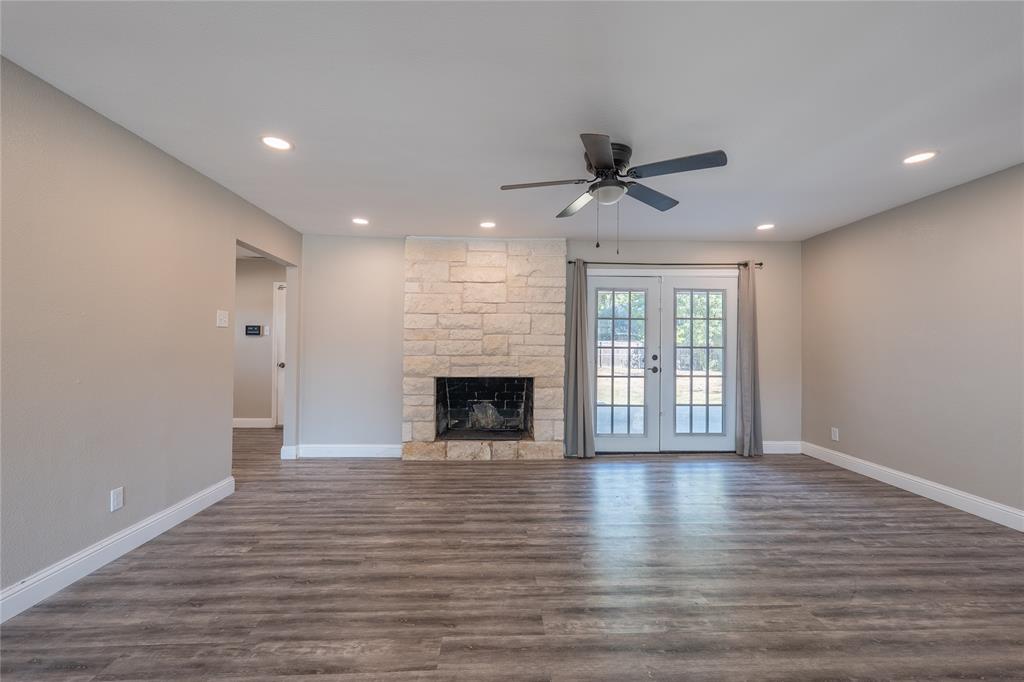 Stone-clad fireplace with a dark firebox, wood-finish flooring, recessed lighting, and a ceiling fan