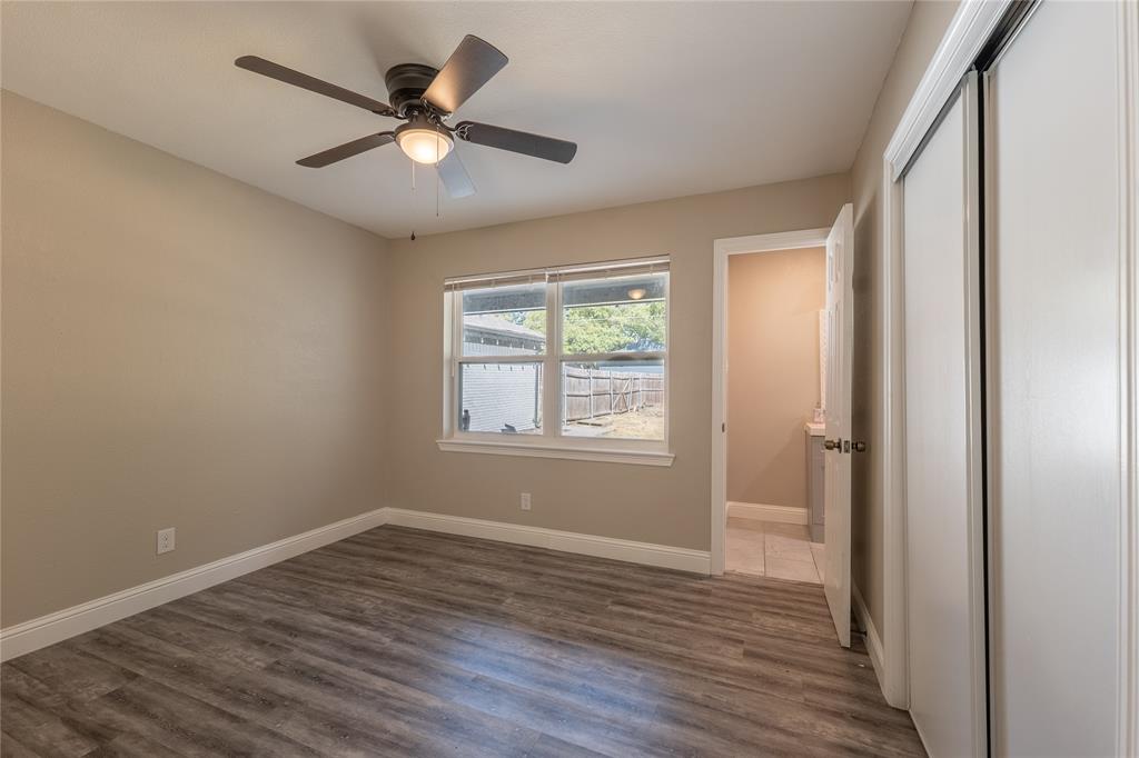 Wood-finish flooring, ceiling fan with integrated lighting, window with exterior scenery, and white trim throughout