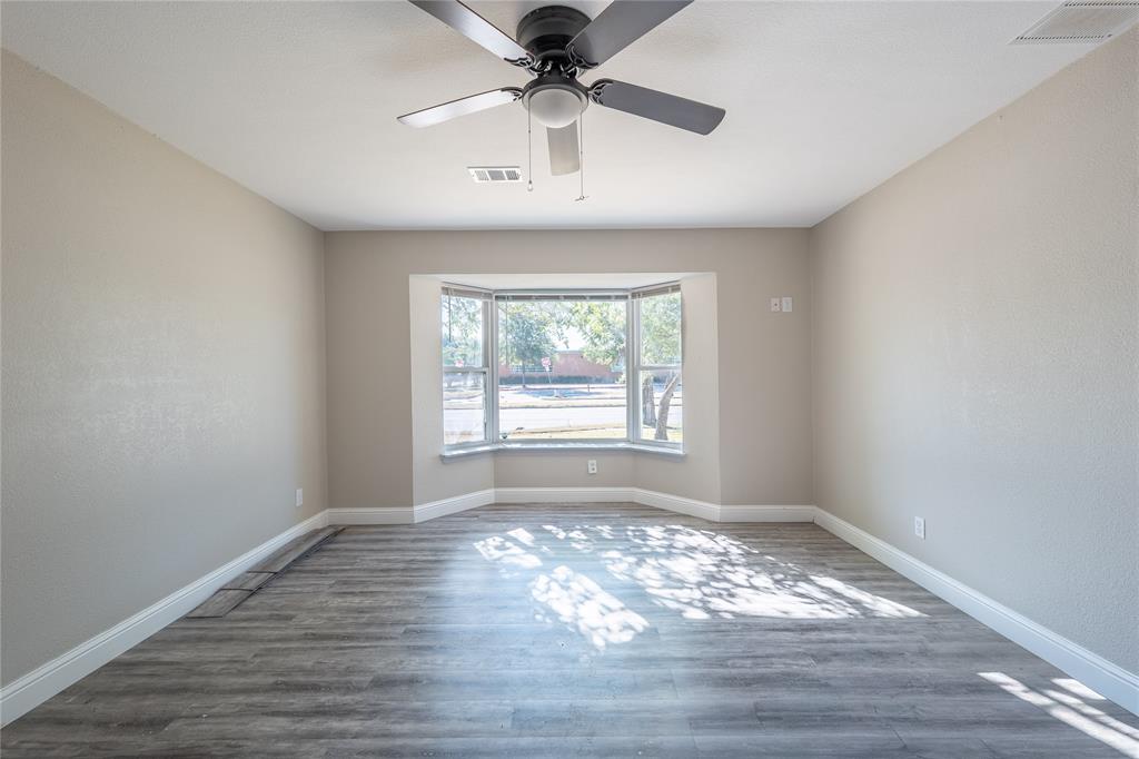 Bay window, ceiling fan, wood-finish flooring, neutral wall tones, white trim
