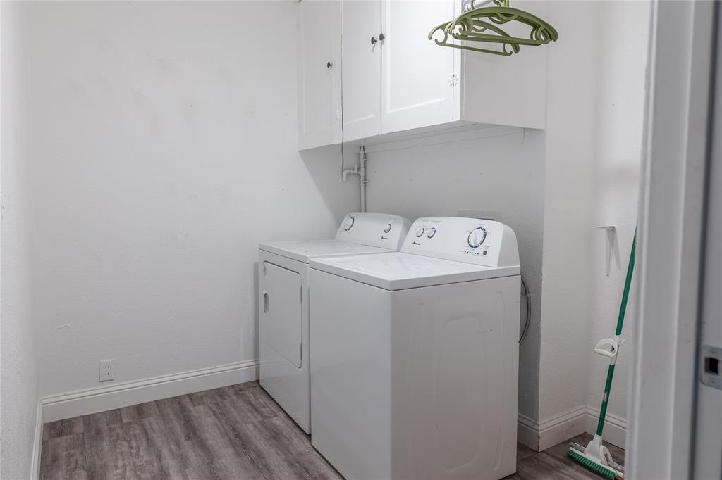 Laundry area featuring wood-finish flooring, white cabinetry, and a utility shelf