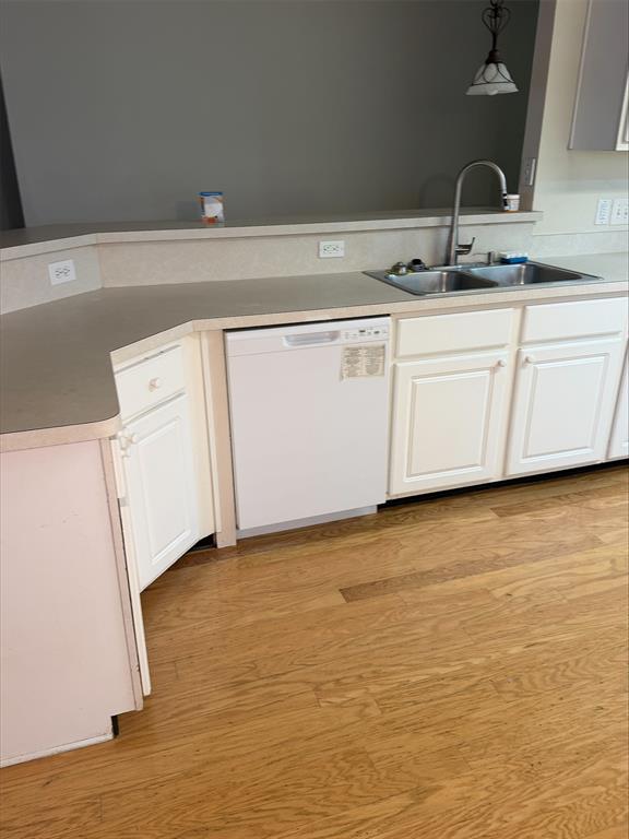 Kitchen featuring white cabinetry, dual basin sink with gooseneck faucet, light-toned countertops, and wood-finish flooring