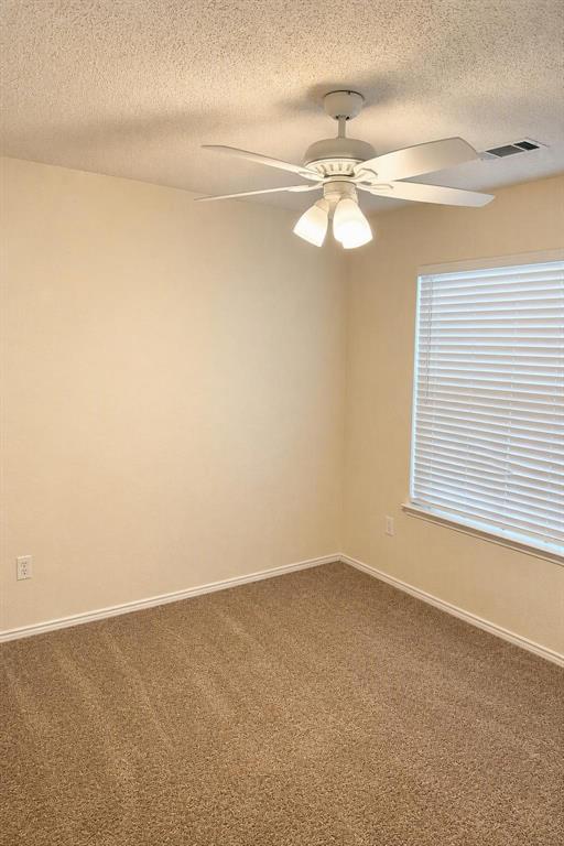 Textured ceiling with a ceiling fan light fixture, neutral wall paint, and carpet flooring