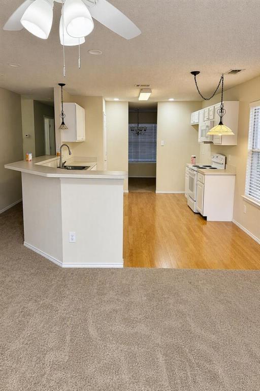 Kitchen with white cabinetry, light-toned countertops, and wood-finish flooring