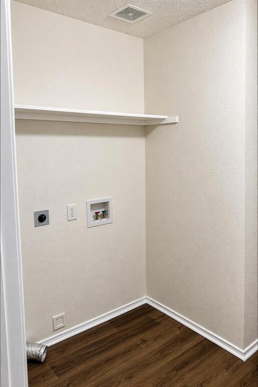 Dedicated utility area featuring a built-in shelf, wood-finish flooring, and essential appliance hookups