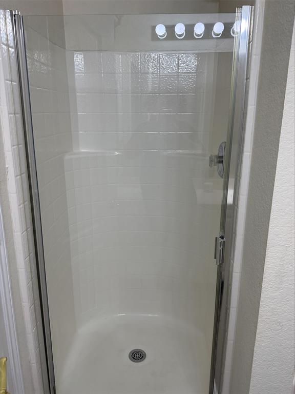 Walk-in shower featuring a chrome showerhead, a built-in seat, and a clear glass enclosure