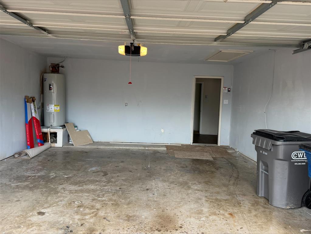 Garage space featuring a water heater, an overhead garage door opener, and a ceiling access panel