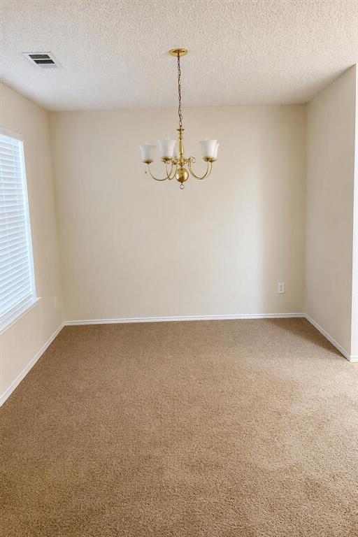 Ceiling-mounted chandelier with four frosted glass shades, textured ceiling, light-toned walls, and neutral carpeting