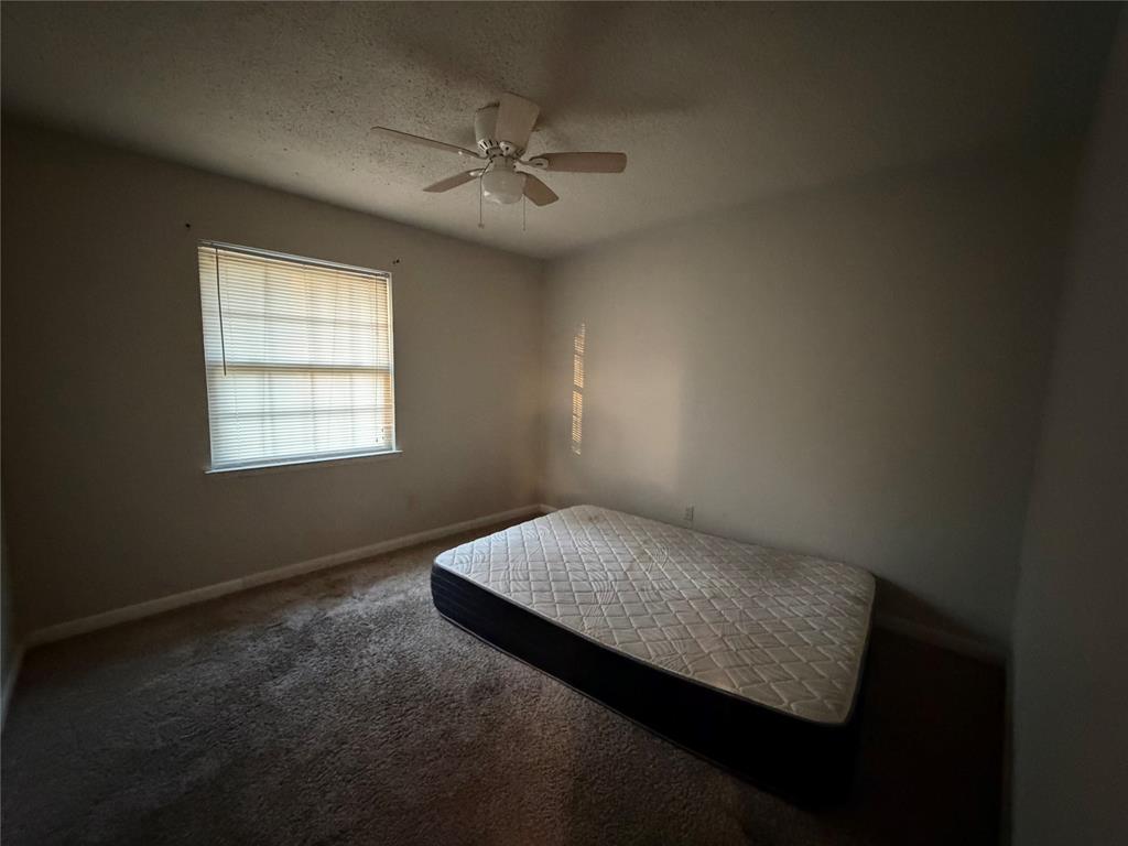 Carpeted room featuring a window with blinds and a ceiling fan with integrated lighting