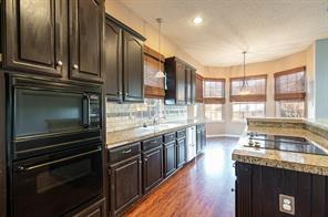 Kitchen with black appliances, dark wood finished floors, light countertops, decorative backsplash, and a sink