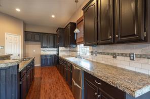 Kitchen with dark brown cabinets, dark wood-style floors, decorative backsplash, and recessed lighting