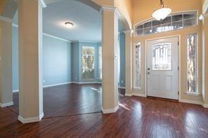 Foyer entrance featuring ornate columns, wood finished floors, baseboards, and ornamental molding