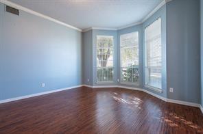 Spare room featuring crown molding, healthy amount of natural light, wood finished floors, and baseboards