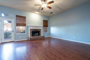 Unfurnished living room featuring lofted ceiling, ceiling fan, baseboards, wood finished floors, and a fireplace