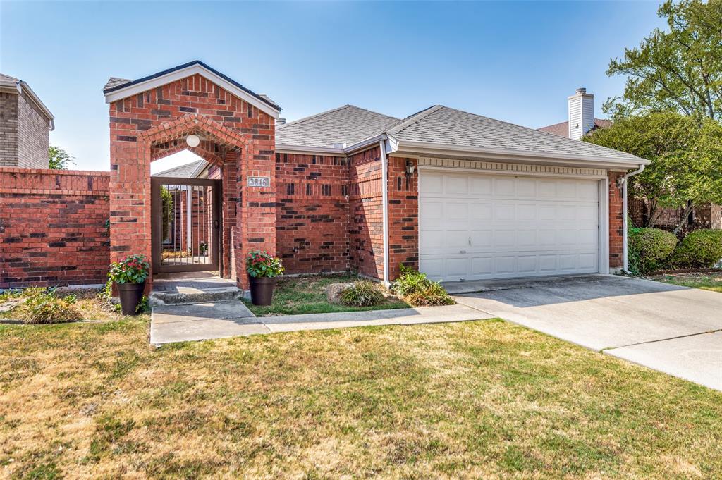 Brick exterior with an arched entryway, wrought iron gate, attached garage, and concrete driveway Brick exterior with an arched entryway, wrought iron gate, attached garage, and concrete driveway