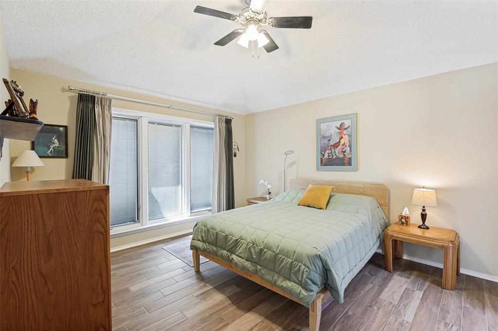 Triple window with blinds, wood-finish flooring, ceiling fan, and neutral wall tones