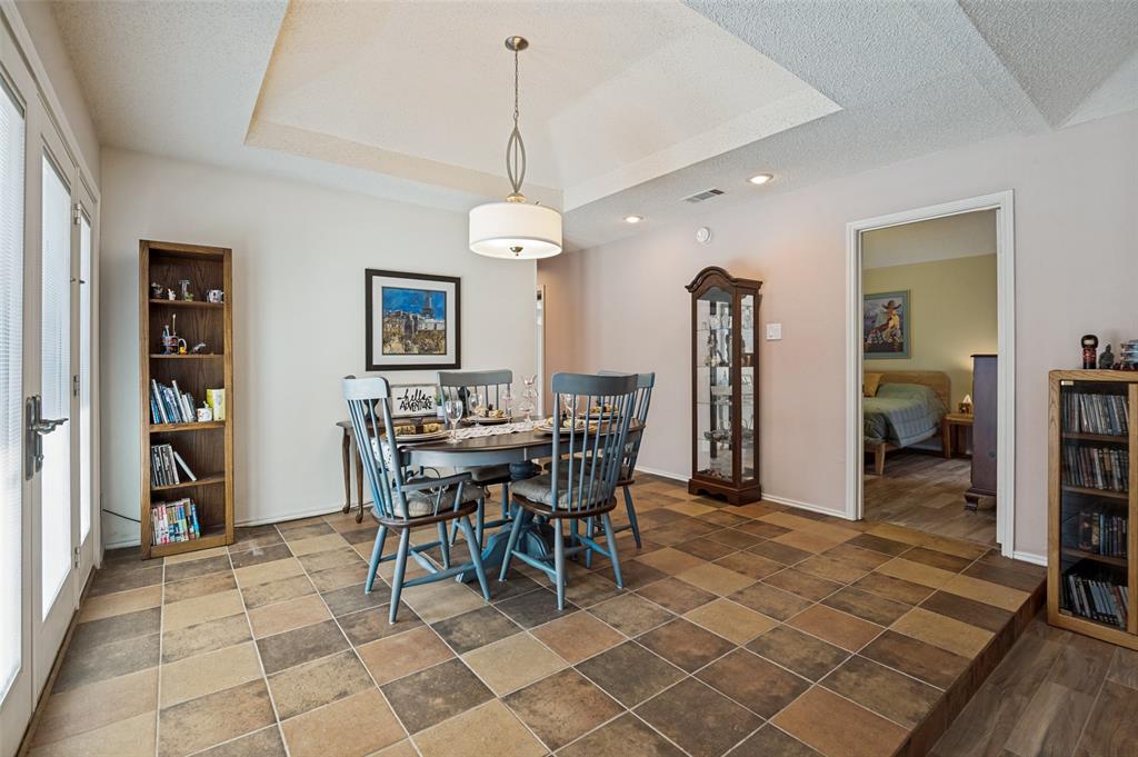 Dining area with multi-tone tile flooring, tray ceiling, recessed lighting, and a drum pendant light fixture