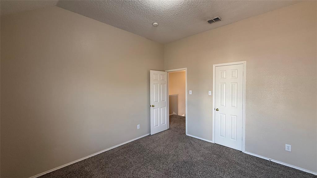 Plush carpeting, neutral wall finishes, white six-panel doors, and a vaulted ceiling