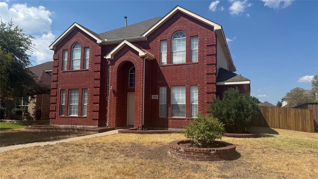 Red brick exterior with white trim, arched entryway, and multiple windows