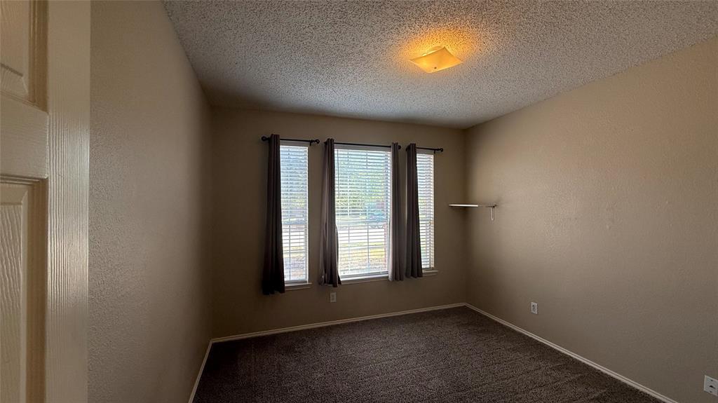Room featuring neutral wall tones, textured ceiling, and dark carpet