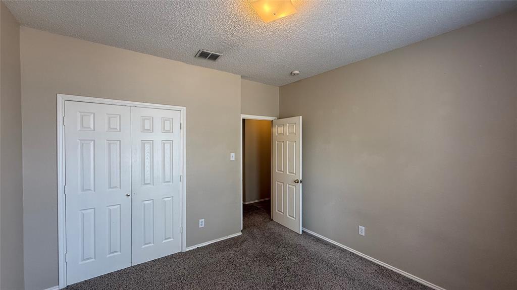 Neutral wall paint, textured ceiling, carpeted flooring, and a flush-mount light fixture