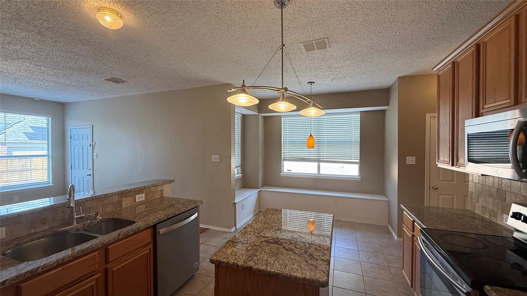 Kitchen featuring a double basin sink, stainless steel dishwasher, built-in microwave, and a breakfast bar with granite countertops