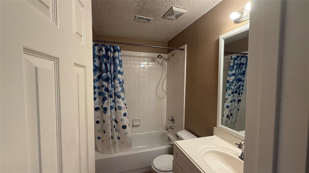 Tub and shower combination with white subway tile surround, single vanity with integrated sink, and framed mirror