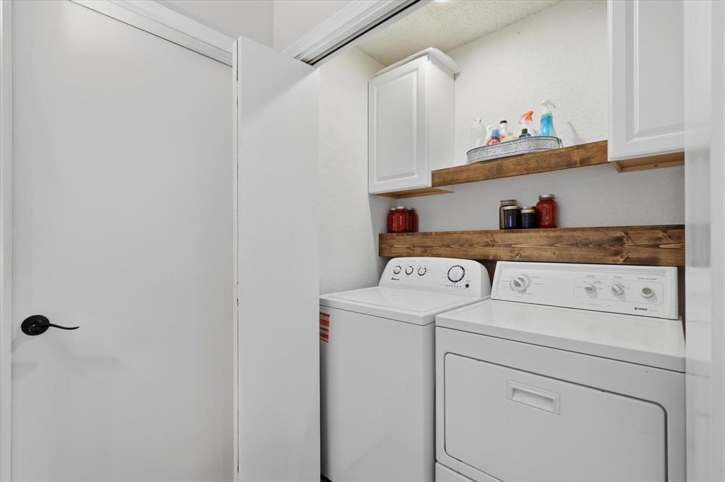 Convenient laundry area offers full-size washer and dryer connections, cabinetry and additional open shelving for storage.