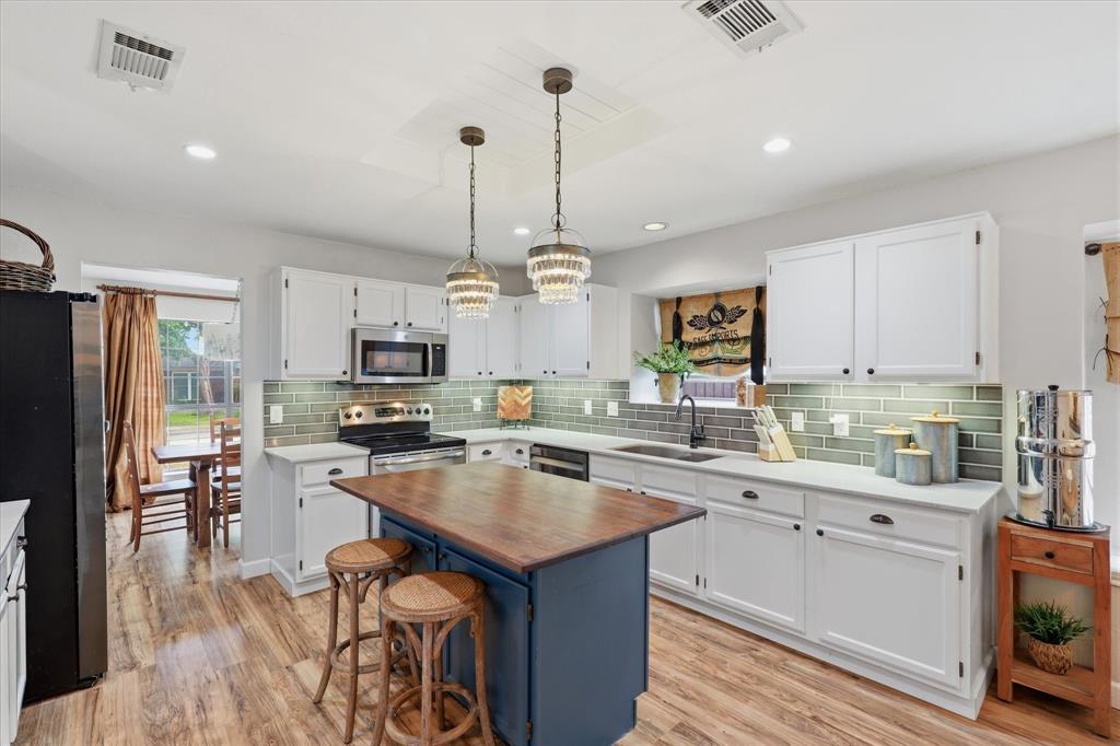 Updated kitchen features white cabinetry, quartz countertops, stainless steel appliances, tile backsplash and a large center island.
