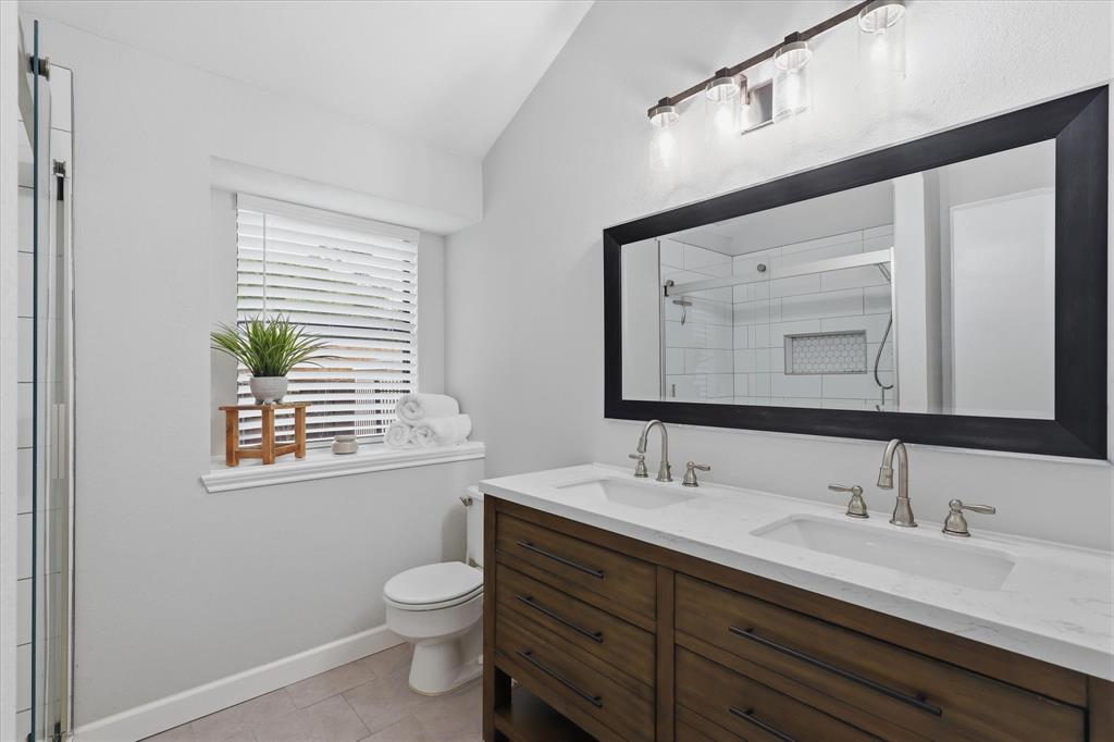 Beautifully updated primary bath features a dual-sink vanity with quartz countertop and an oversized mirror.