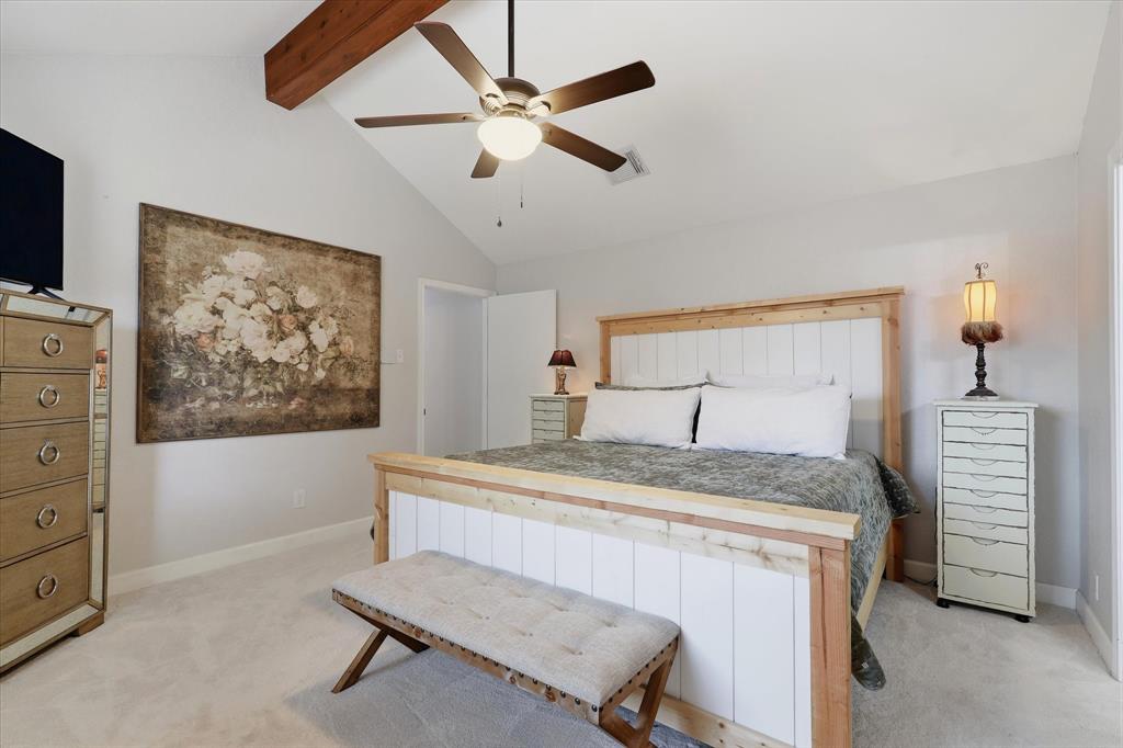 Vaulted ceilings and an exposed wood beam add architectural character to the spacious primary retreat.
