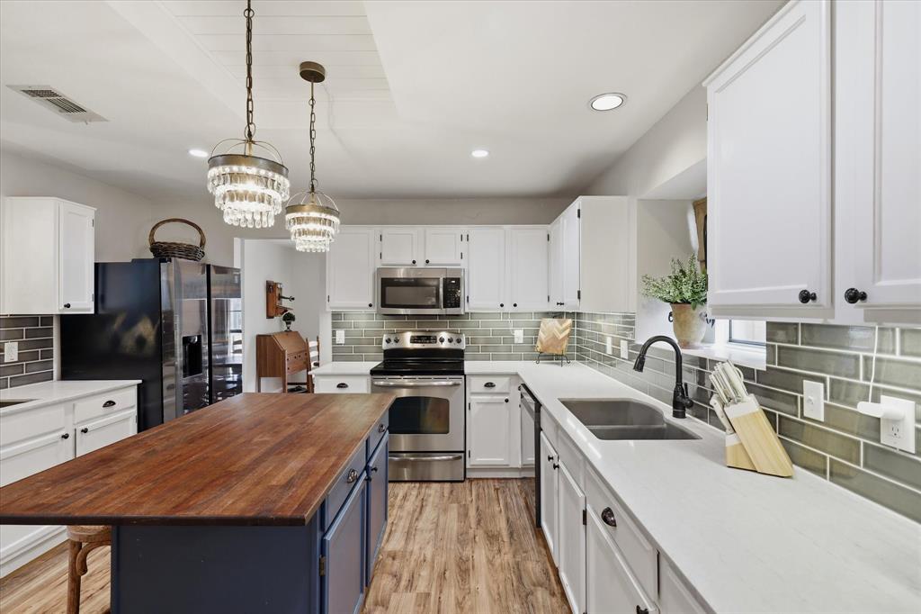 Large center island adds valuable workspace and casual seating beneath decorative pendant lighting.