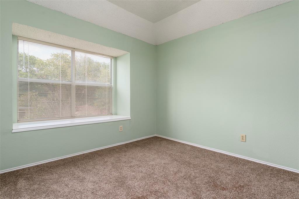 Textured carpet flooring, window with blinds, and tray ceiling detail