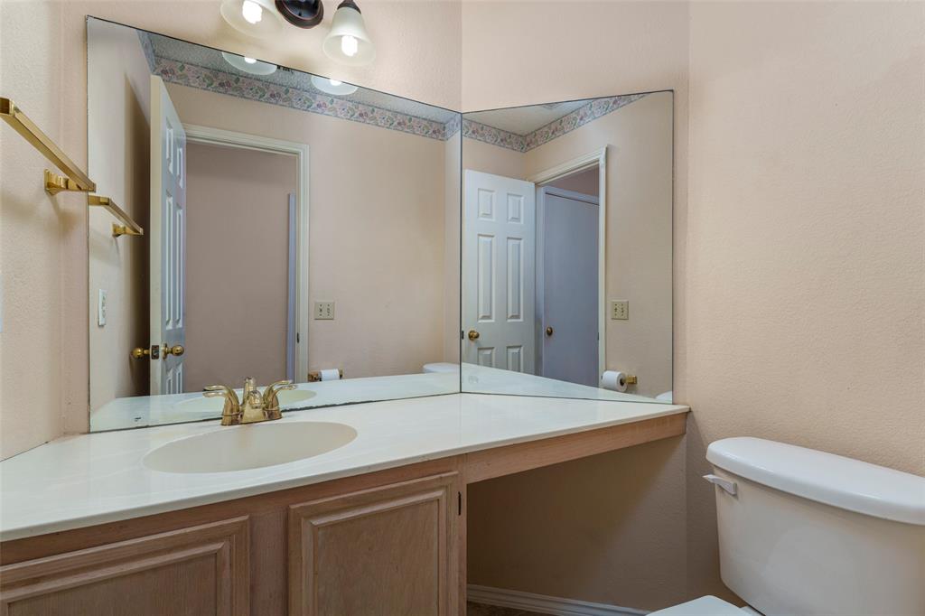 Bathroom featuring a corner vanity with an integrated sink, dual-paneled mirror, and a brass-finish faucet
