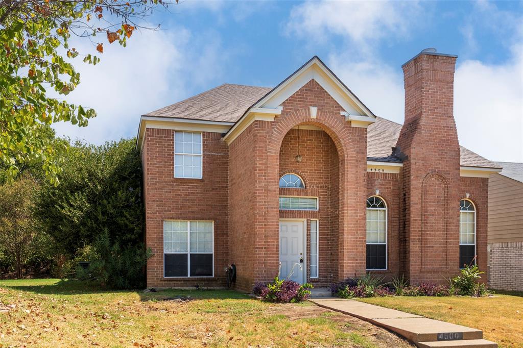 Brick exterior with an arched entry, prominent brick chimney, and a concrete pathway leading to the front door