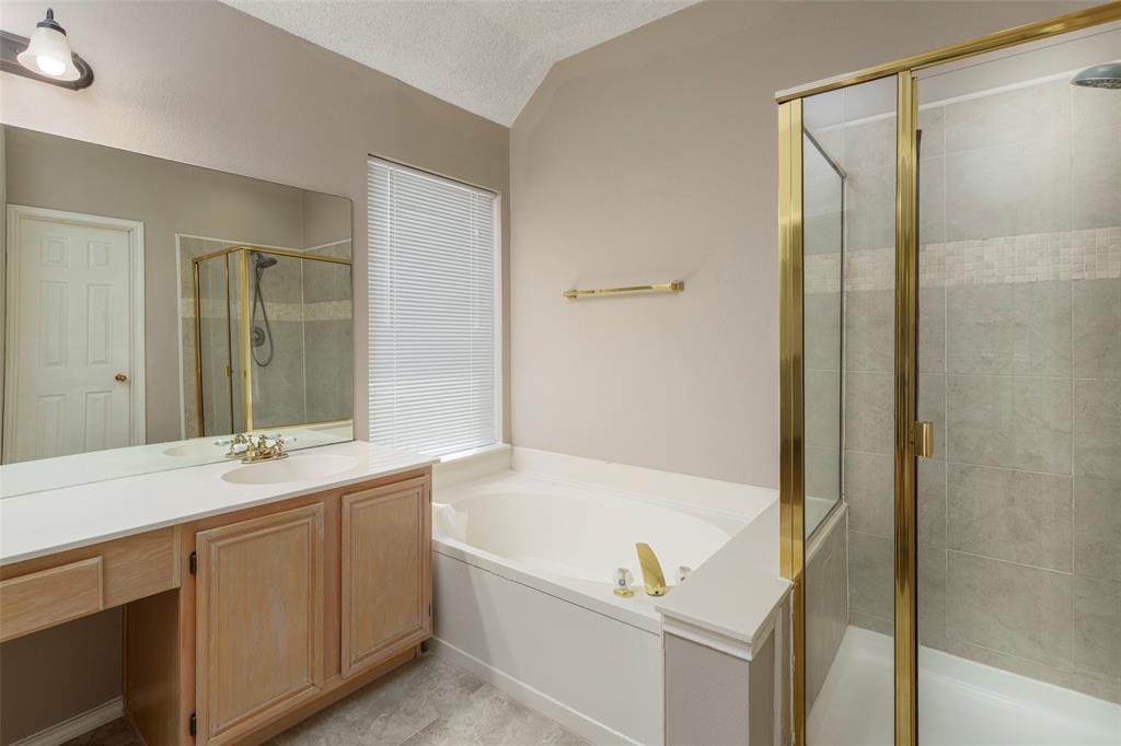 Vanity with integrated sink, built-in bathtub, and enclosed shower with tile surround