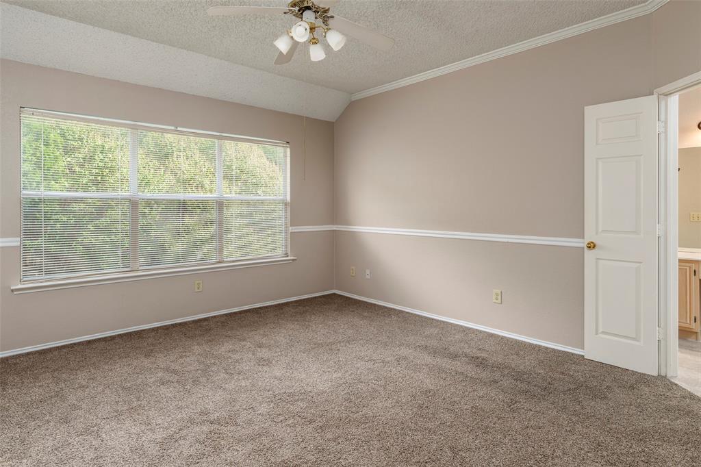 Vaulted ceiling with ceiling fan, large window with blinds, chair rail molding, and carpet flooring