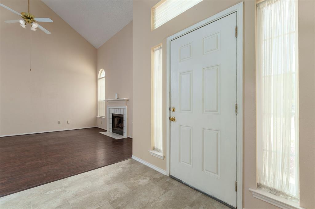 Vaulted ceiling, ceiling fan, fireplace with mantel, arched window, wood-finish flooring