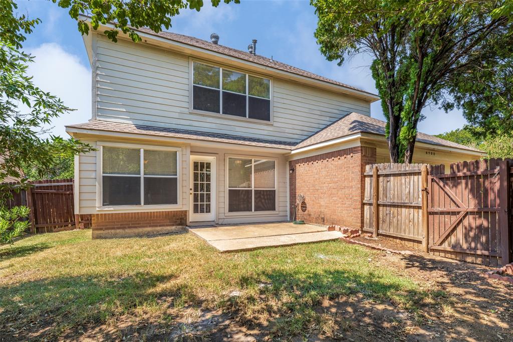 Back exterior featuring a concrete patio, wood fencing, brick and siding exterior, and a glass-paneled door