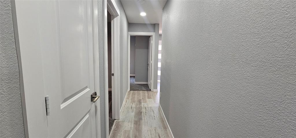 Hallway featuring wood-finish flooring, recessed lighting, and panel doors with lever hardware