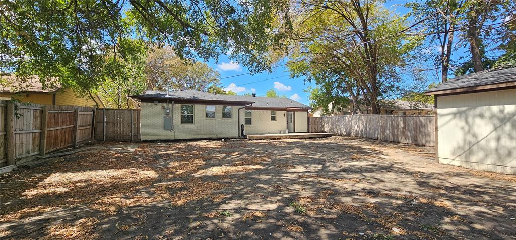 Expansive backyard featuring a wood deck, wood privacy fencing, and a detached structure