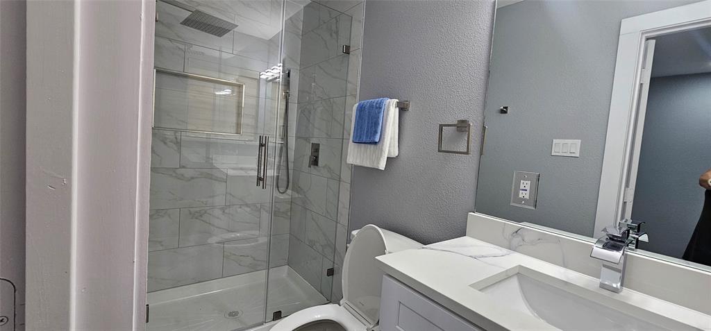 Glass-enclosed shower with a rainfall showerhead, tiled walls, and a built-in shower niche