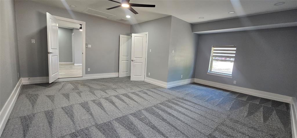 Spacious room with patterned carpet flooring, ceiling fan, recessed lighting, and a window with blinds