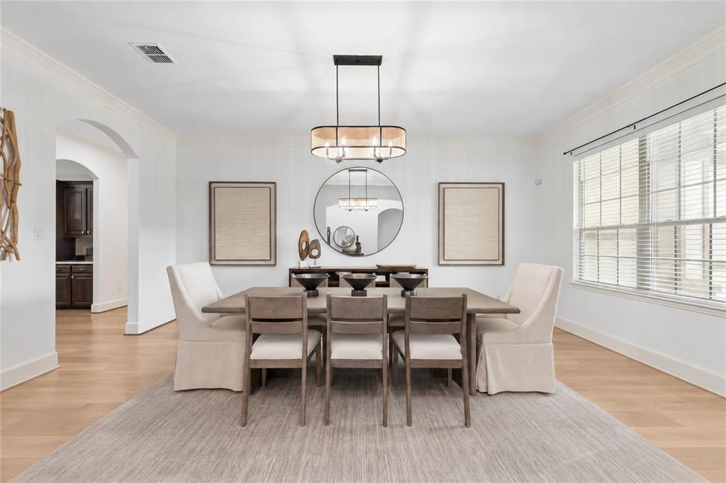 Expansive dining area featuring crown molding, wood-finish flooring, and a contemporary chandelier