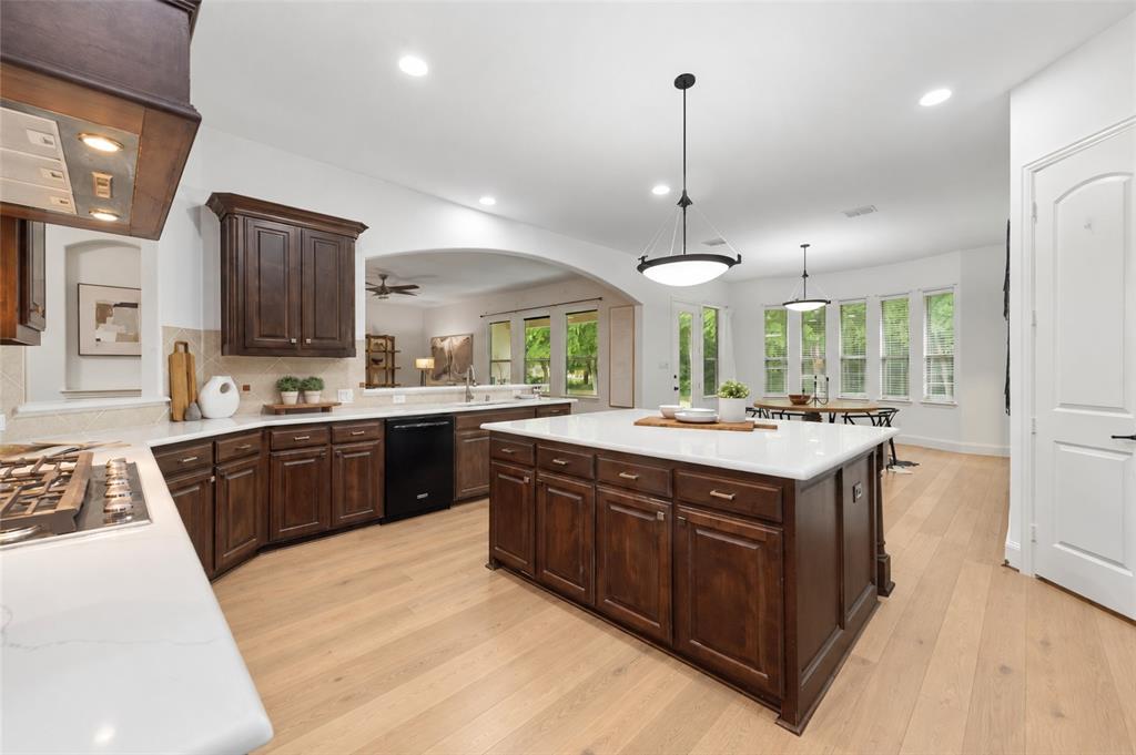 Kitchen featuring wood-finish flooring, dark wood cabinetry, light countertops, and a central island