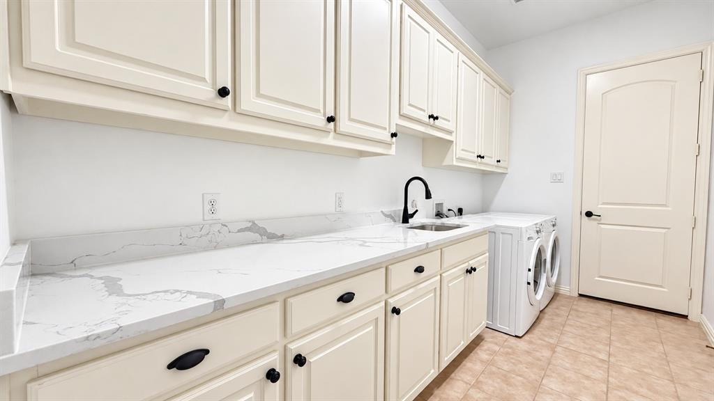 Extensive countertop space featuring a dual-basin sink, white shaker-style cabinetry with matte black hardware, and tiled flooring