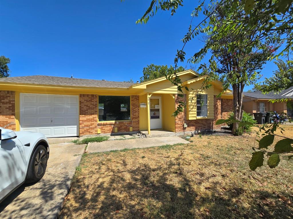 Brick exterior with yellow siding accents, an attached garage, and a concrete driveway