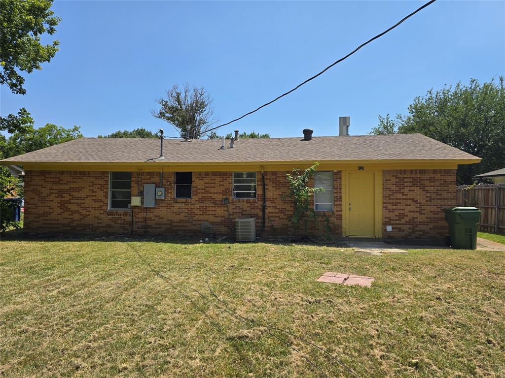 Brick exterior with a brown shingle roof, yellow trim, and a yellow door