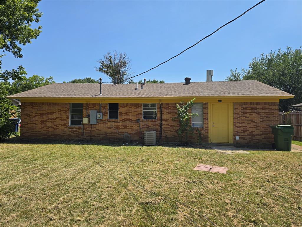 Brick exterior with a yellow door and a shingled roof