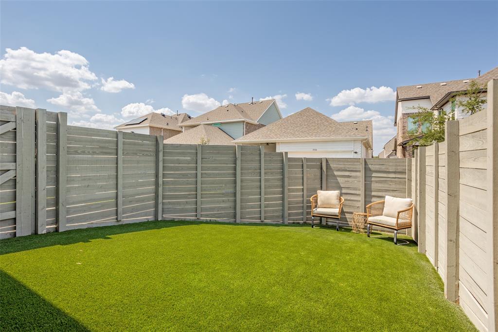 Enclosed backyard featuring a privacy fence, artificial turf, and a gated entry